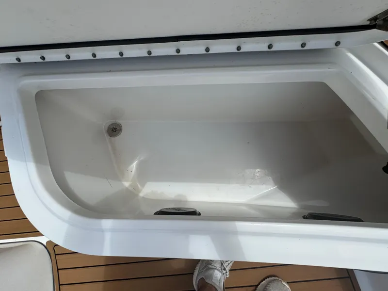Slide: The Image of Open storage compartment on 2019 World Cat 3200 boat, featuring white interior and wooden deck. - 34