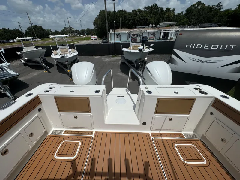 Slide: The Image of 2019 World Cat 3200 boat deck with wood finish, surrounded by other boats and a trailer. - 76