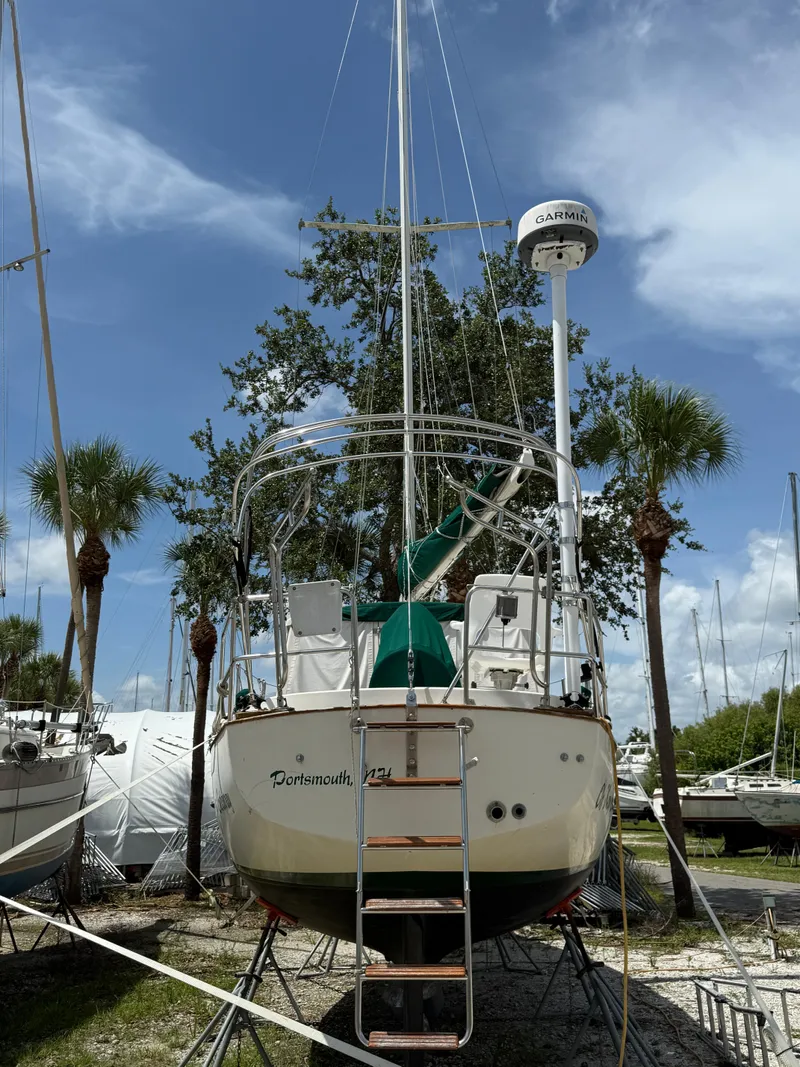 Slide: The Image of 1994 Pacific Seacraft Pilothouse 32 sailboat on land, surrounded by palm trees and clear sky. - 22