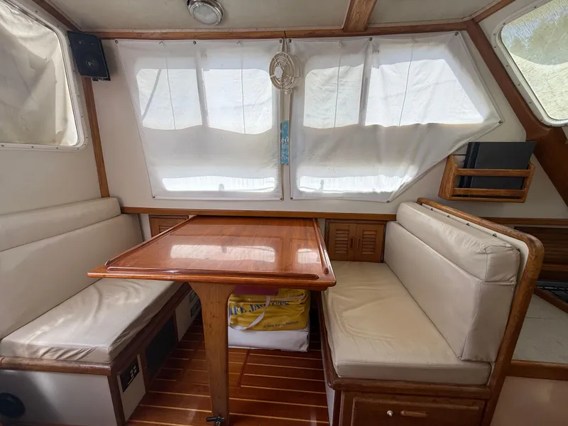 Slide: The Image of Interior of 1994 Pacific Seacraft Pilothouse 32 with wooden table and cushioned seating. - 6