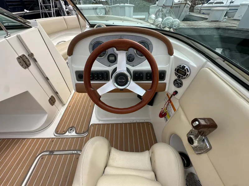 Slide: The Image of 2008 Chris-Craft Launch 25 boat interior with wooden steering wheel and beige seating. - 14