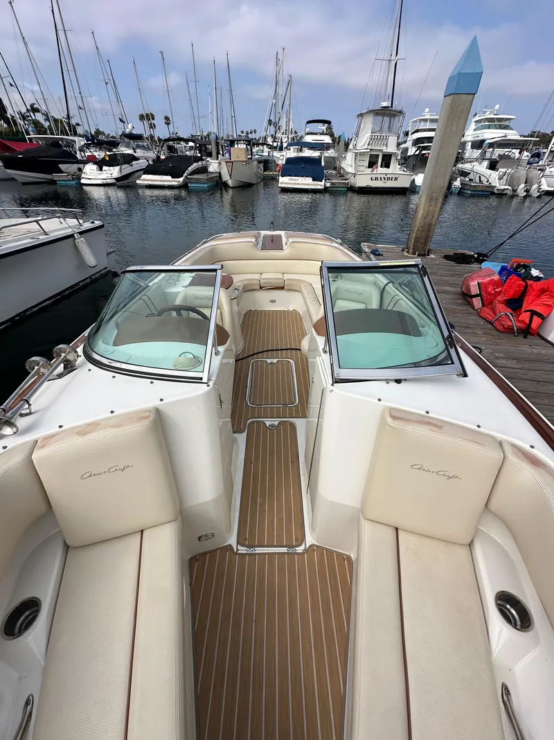 Slide: The Image of 2008 Chris-Craft Launch 25 boat docked in marina, featuring elegant seating and wooden deck. - 24