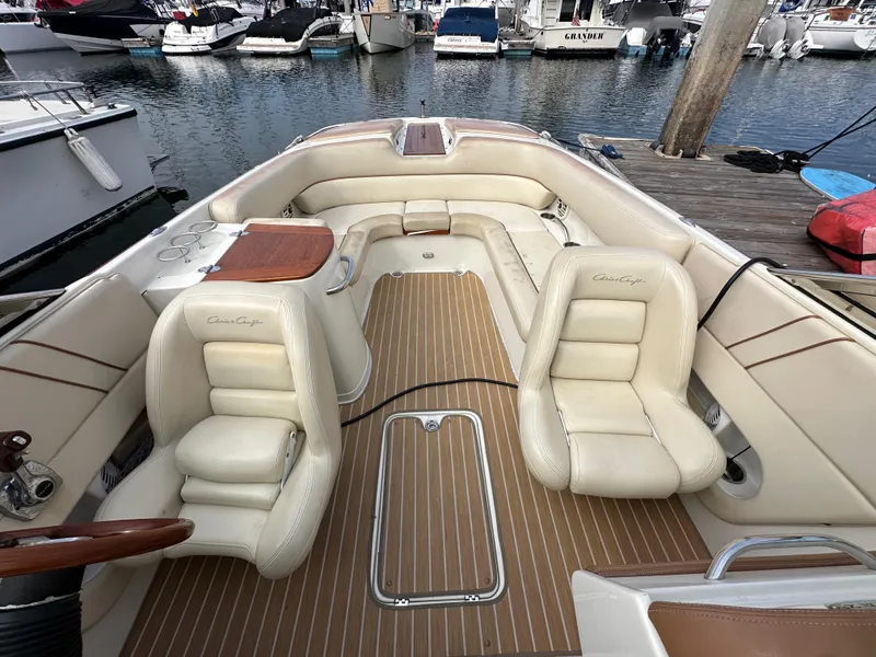 Slide: The Image of 2008 Chris-Craft Launch 25 boat interior with cream leather seats and wooden accents at a marina. - 25
