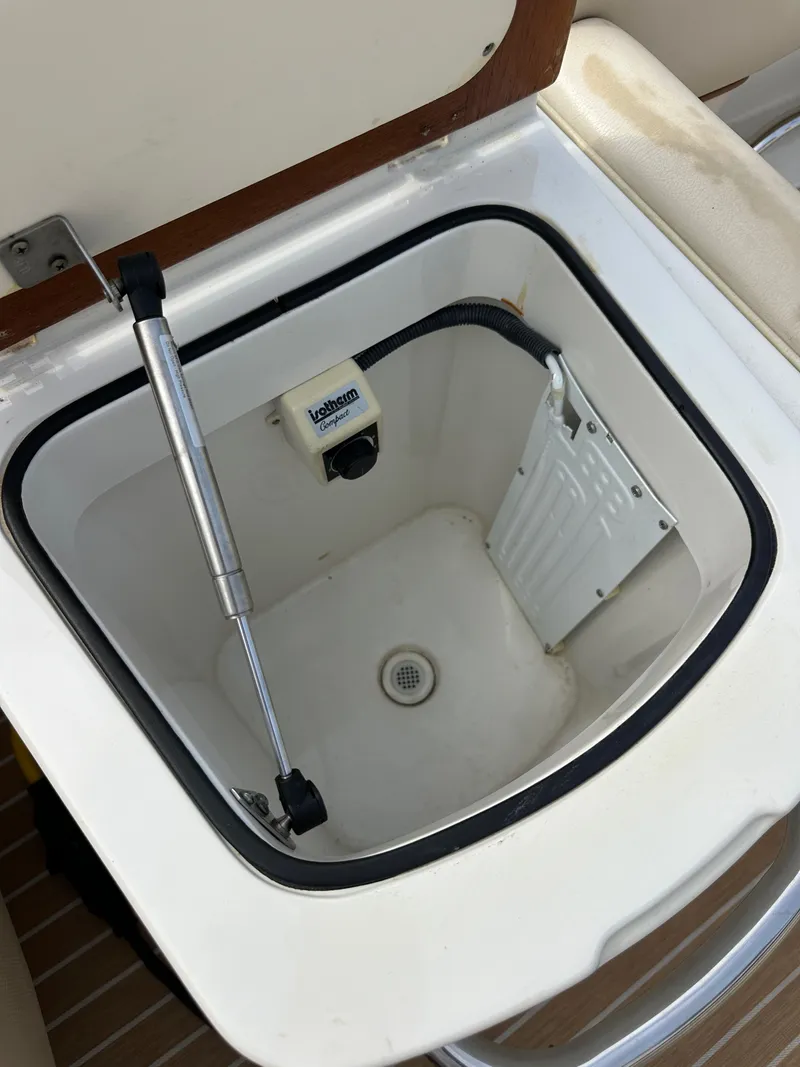 Slide: The Image of Storage compartment in a 2008 Chris-Craft Launch 25 boat, featuring a drain and hydraulic support. - 27