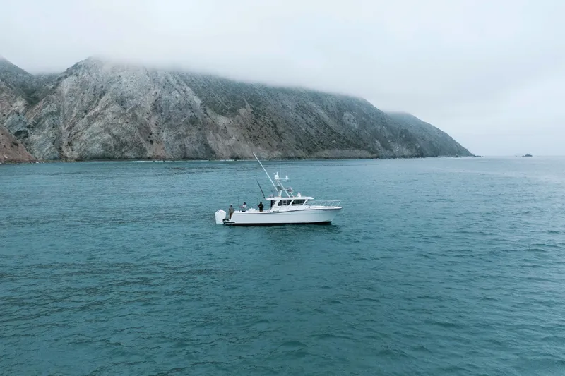 Slide: The Image of 2025 Lindell 41' boat cruising near rocky coastline under cloudy sky. - 4