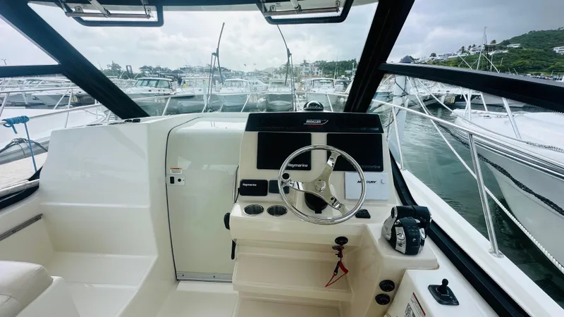 Slide: The Image of 2021 Boston Whaler 325 Conquest helm with modern controls and marina view. - 10