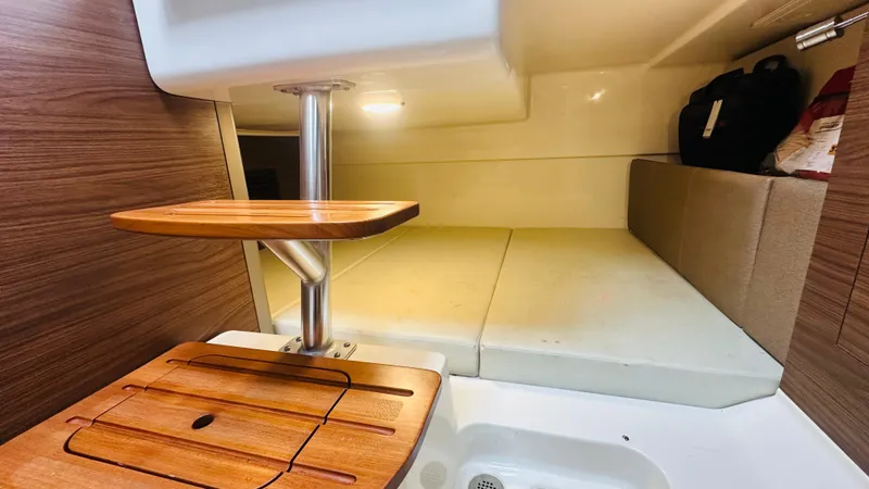 Slide: The Image of 2021 Boston Whaler 325 Conquest cabin interior with wooden table and cushioned seating. - 11