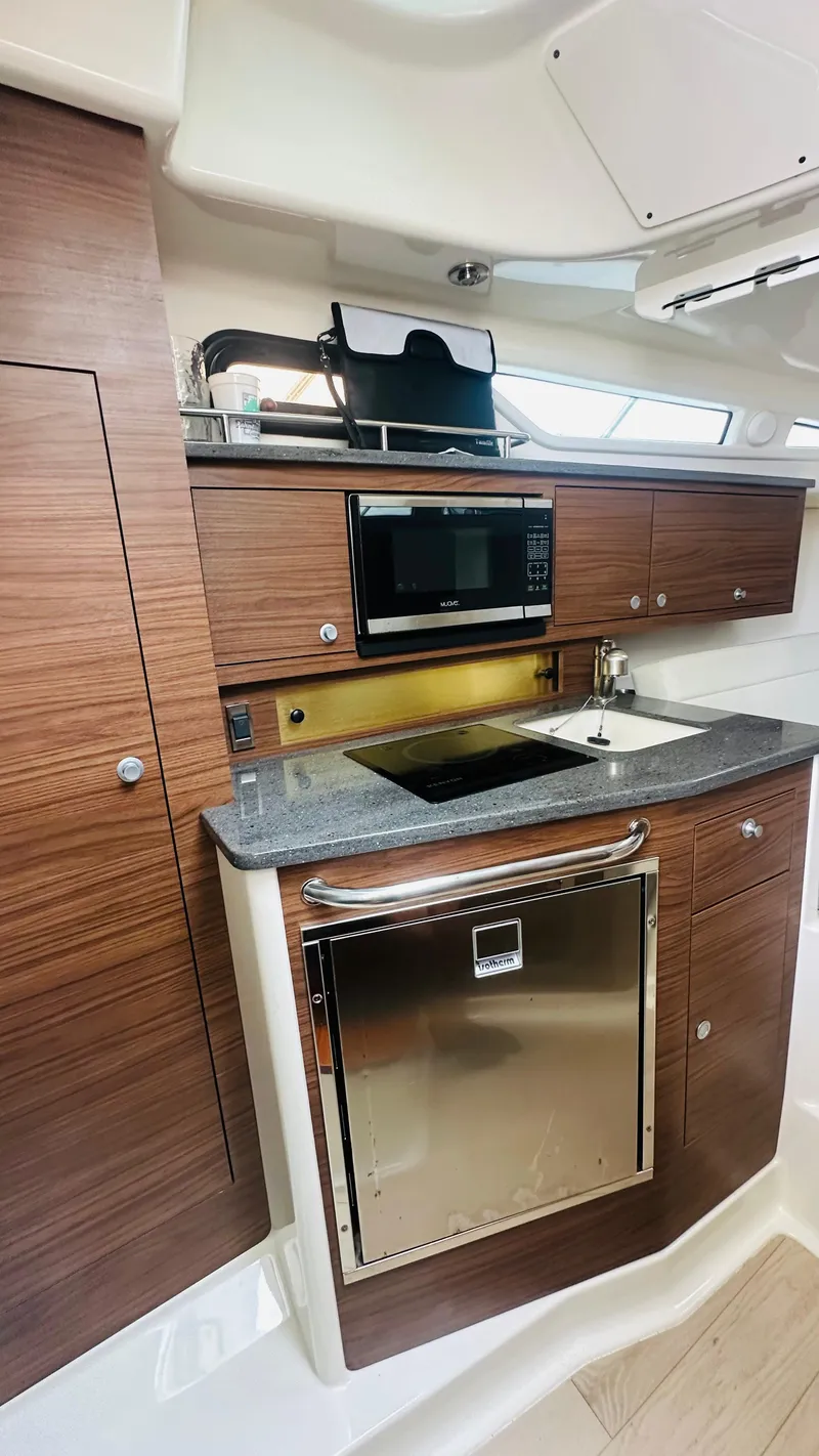 Slide: The Image of 2021 Boston Whaler 325 Conquest kitchen with modern appliances and wood cabinetry. - 12