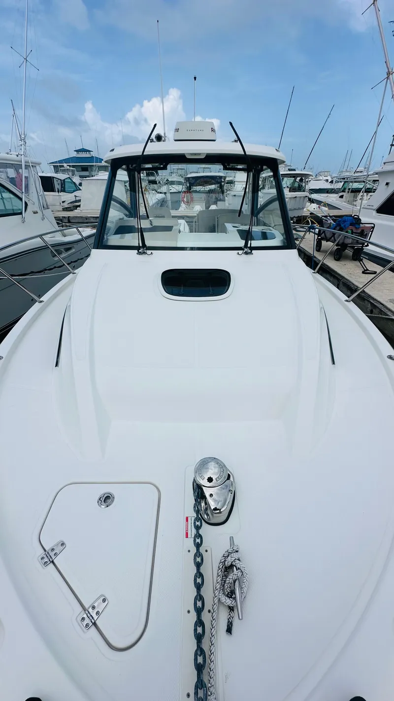 Slide: The Image of 2021 Boston Whaler 325 Conquest boat docked, showcasing sleek design and spacious deck. - 16