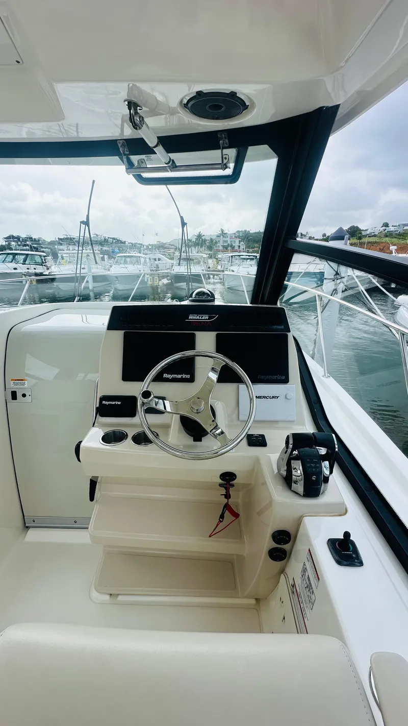 Slide: The Image of 2021 Boston Whaler 325 Conquest helm with steering wheel and controls, docked at marina. - 9