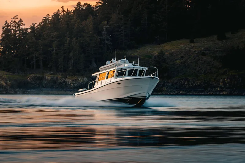 Slide: The Image of 2025 Lindell 42' boat cruising on water at sunset near forested shoreline. - 4