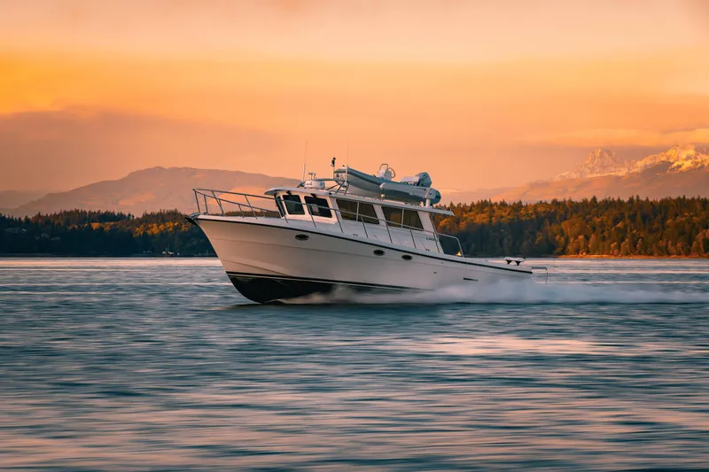 Slide: The Image of 2025 Lindell 42' boat cruising on water at sunset near forested shoreline. - 3