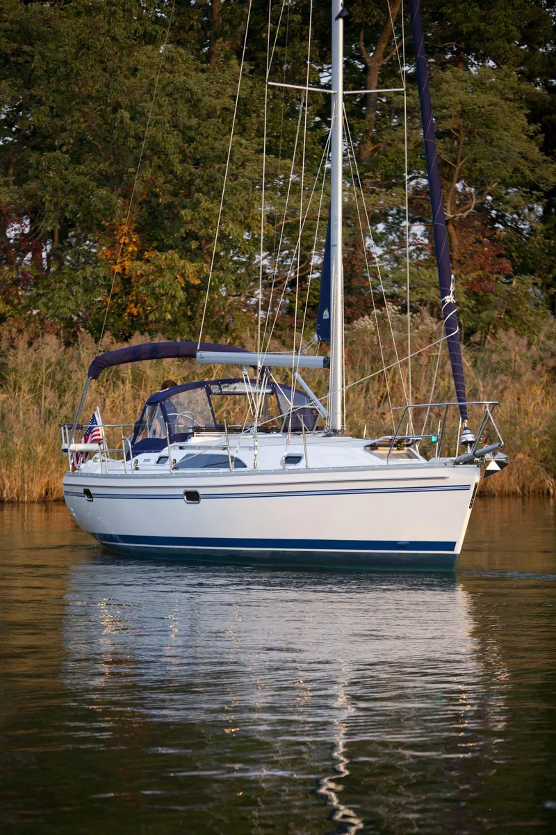 Slide: The Image of 2024 Catalina 355 sailboat on calm water with trees in the background. - 12