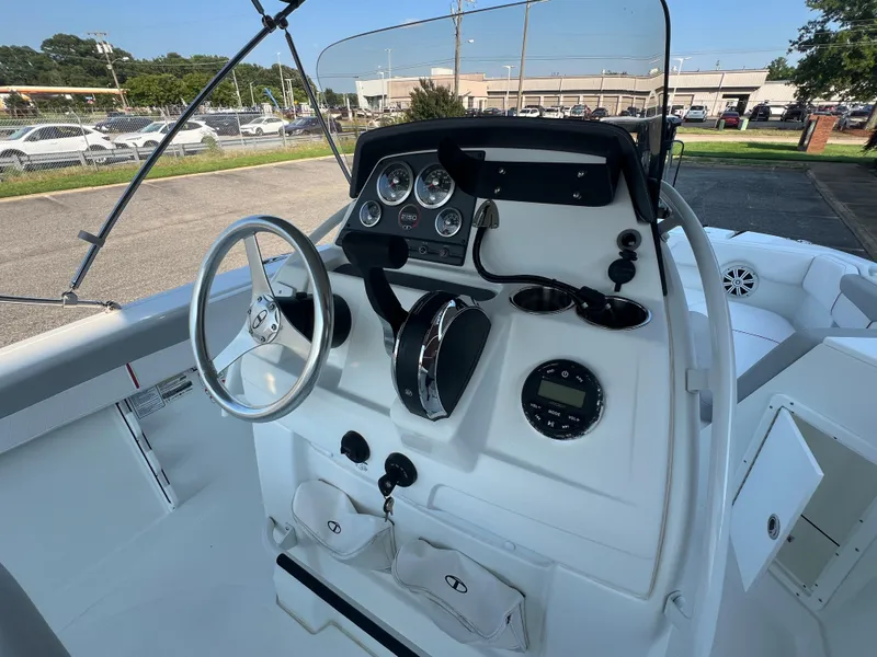 Slide: The Image of 2020 Tahoe 2150 CC boat dashboard with steering wheel and gauges in a parking lot. - 11