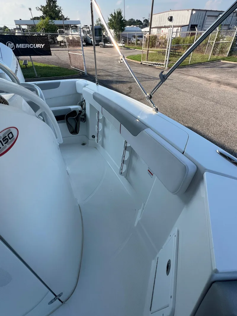 Slide: The Image of 2020 Tahoe 2150 CC boat interior with seating and storage, parked outdoors. - 21