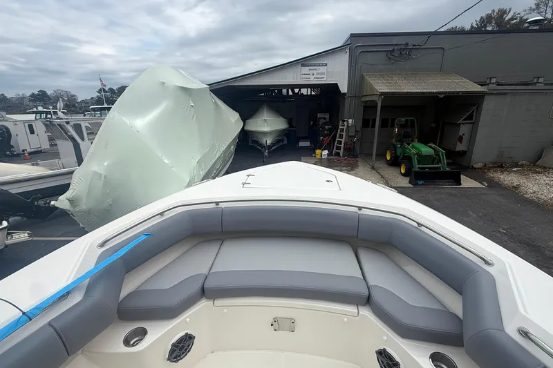 Slide: The Image of 2026 Boston Whaler 280 Outrage boat in storage facility, with covered boats and equipment nearby. - 4