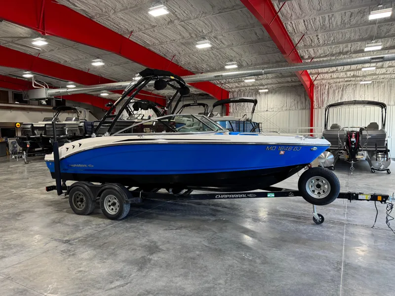 Slide: The Image of 2018 Chaparral 21 H2O boat in showroom, blue and white, on a trailer. - 1