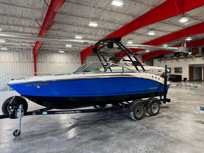 Slide: The Image of 2018 Chaparral 21 H2O boat in a warehouse, blue hull, on a trailer. - 2