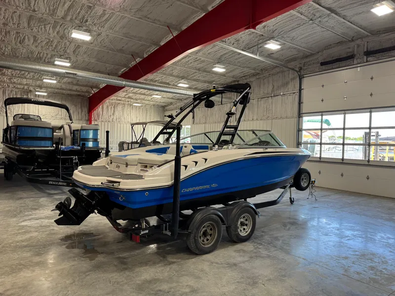 Slide: The Image of 2018 Chaparral 21 H2O boat in a showroom, blue and white, on a trailer. - 3
