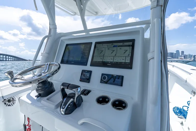 Slide: The Image of 2021 Yellowfin 34 boat dashboard with modern navigation screens and controls, city skyline in background. - 22