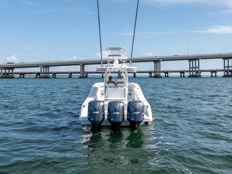 Slide: The Image of 2021 Yellowfin 34 boat with triple engines on open water near a bridge. - 7