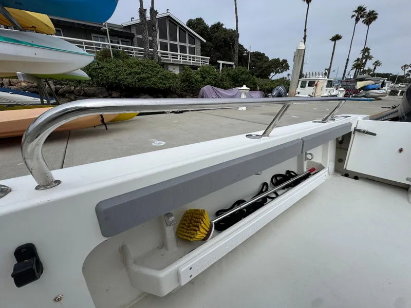 Slide: The Image of 2021 Parker 2520 XLD Sport Cabin boat deck with storage compartment and cleaning brush. - 16
