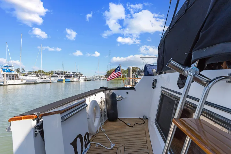 Slide: The Image of 1993 Ocean Alexander 440 yacht docked at marina, featuring American flag and clear blue sky. - 9