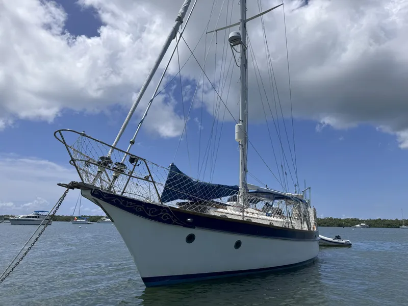 Slide: The Image of 1979 CSY 44 sailboat anchored on calm water under a partly cloudy sky. - 1