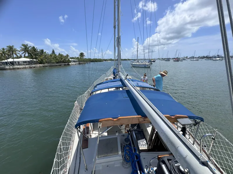 Slide: The Image of 1979 CSY 44 sailboat on calm waters, clear sky, and palm trees in the background. - 10