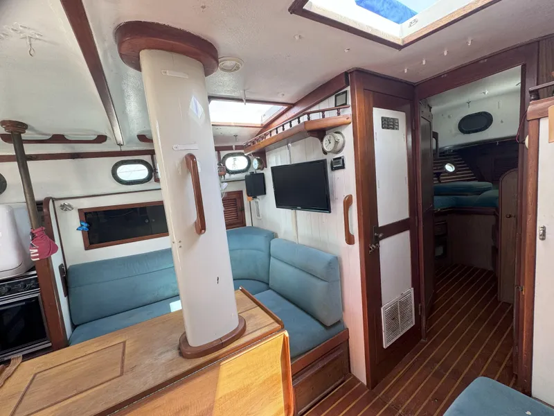 Slide: The Image of 1979 CSY 44 yacht interior with blue seating, wood accents, and a mounted TV. - 12