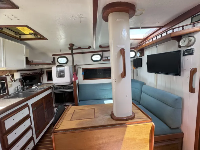 Slide: The Image of 1979 CSY 44 yacht interior with kitchen, seating, and TV. Cozy and well-equipped living space. - 13