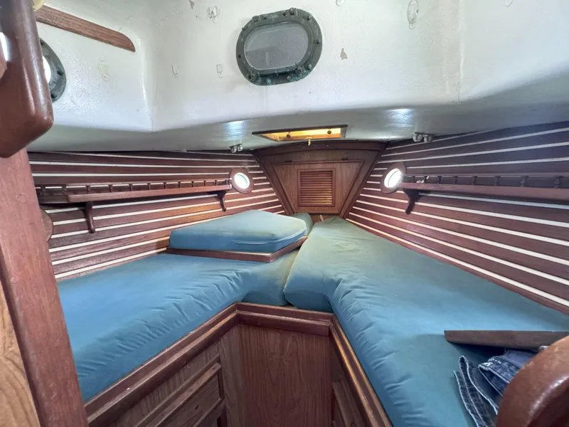 Slide: The Image of 1979 CSY 44 sailboat cabin with blue cushions and wooden interior. - 16