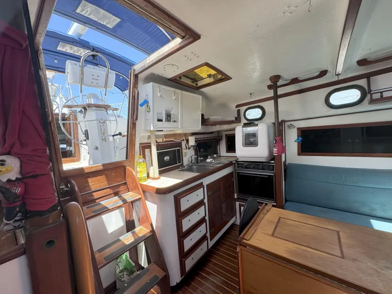 Slide: The Image of Interior of a 1979 CSY 44 sailboat featuring a compact kitchen and seating area. - 19