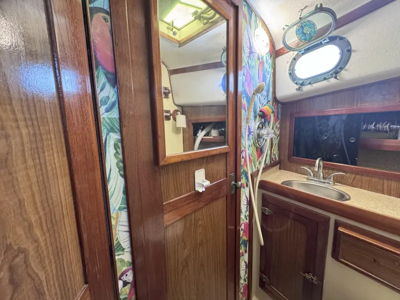 Slide: The Image of 1979 CSY 44 yacht bathroom with wooden cabinetry, colorful wallpaper, and porthole window. - 23