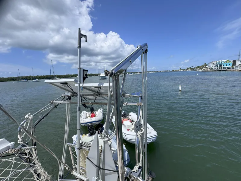 Slide: The Image of Sailboat CSY 44 (1979) with dinghy on calm water, under a partly cloudy sky. - 33