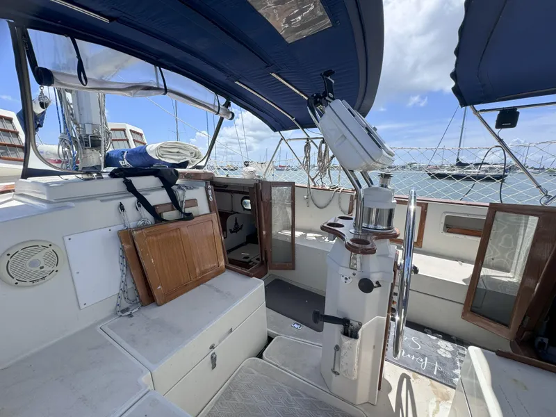 Slide: The Image of 1979 CSY 44 sailboat cockpit with blue canopy, steering wheel, and open storage compartments. - 9