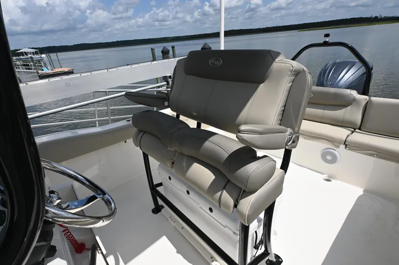 Slide: The Image of 2024 Key West 239 FS boat interior with comfortable seating and steering wheel, docked by the water. - 8
