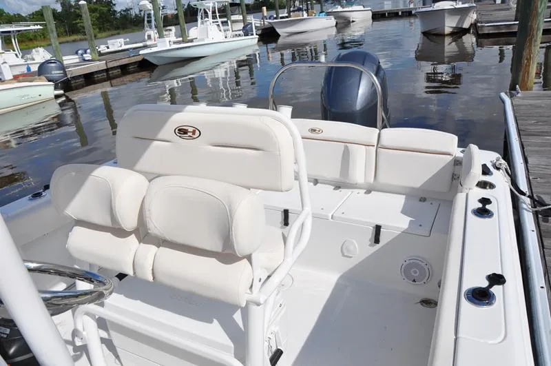 Slide: The Image of 2020 Sea Hunt Ultra 225 boat interior at marina, featuring white seating and steering console. - 13