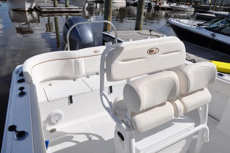 Slide: The Image of 2020 Sea Hunt Ultra 225 boat interior with white seating at a marina. - 14