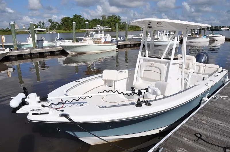 Slide: The Image of 2020 Sea Hunt Ultra 225 boat docked at marina under clear skies. - 2