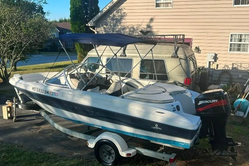 The Image of 2002 Bayliner 184 SF boat with Mercury outboard motor on trailer, parked in driveway. - 0