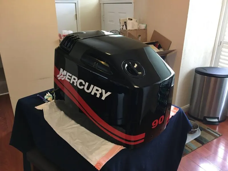 Slide: The Image of Mercury 90 outboard motor cover on table, indoors, near Bayliner 184 SF, 2002 model. - 11