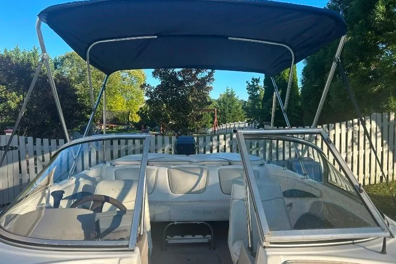 Slide: The Image of 2002 Bayliner 184 SF boat with canopy, parked outdoors near a white fence. - 19