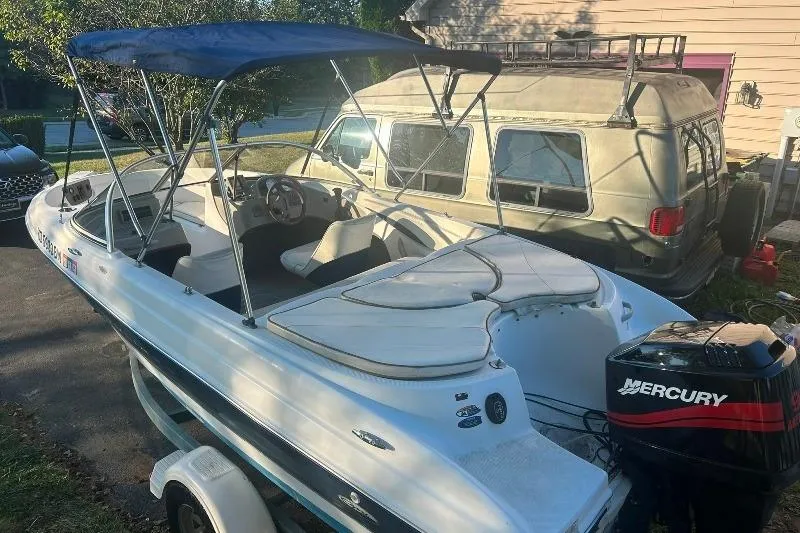 Slide: The Image of 2002 Bayliner 184 SF boat with Mercury outboard motor, parked beside a van. - 2