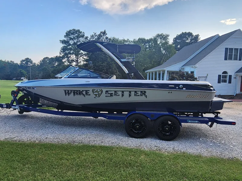 Slide: The Image of 2013 Malibu Wakesetter 23 LSV boat on trailer, parked near a house. - 2