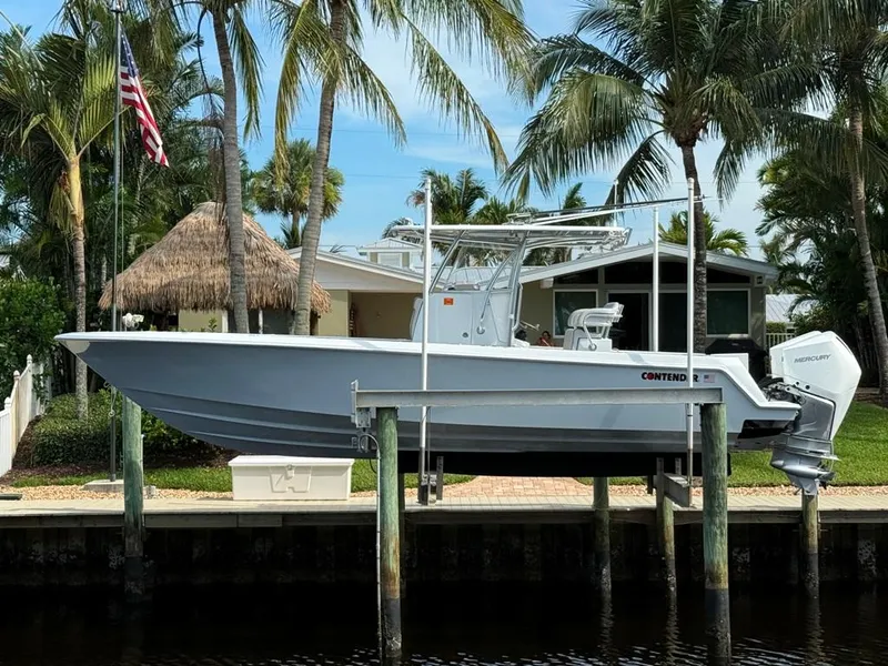 The Image of 2023 Contender 30 Tournament boat docked near palm trees and a house. - 1