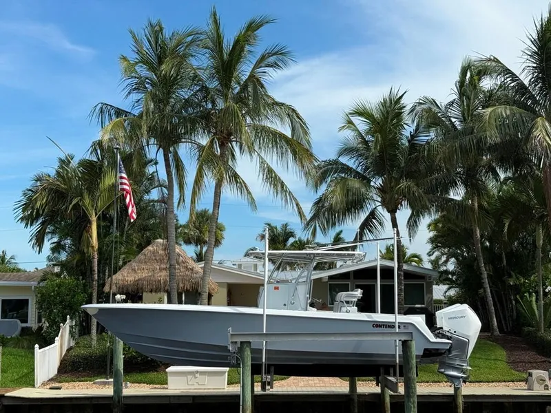 Slide: The Image of 2023 Contender 30 Tournament boat docked near palm trees and a house. - 3