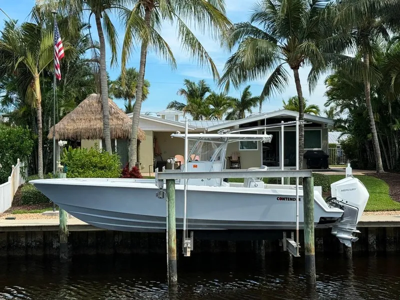 Slide: The Image of 2023 Contender 30 Tournament boat docked by palm trees and a waterfront home. - 5