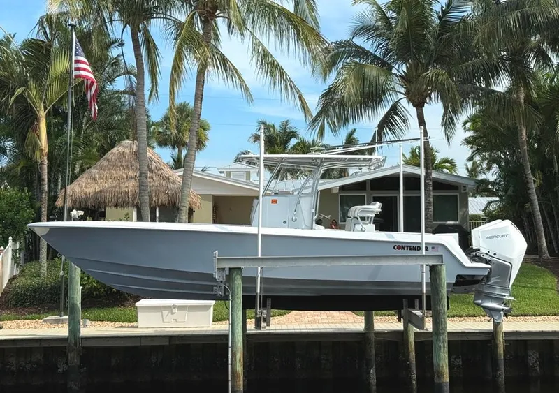 Slide: The Image of 2023 Contender 30 Tournament boat docked near palm trees and a house. - 6