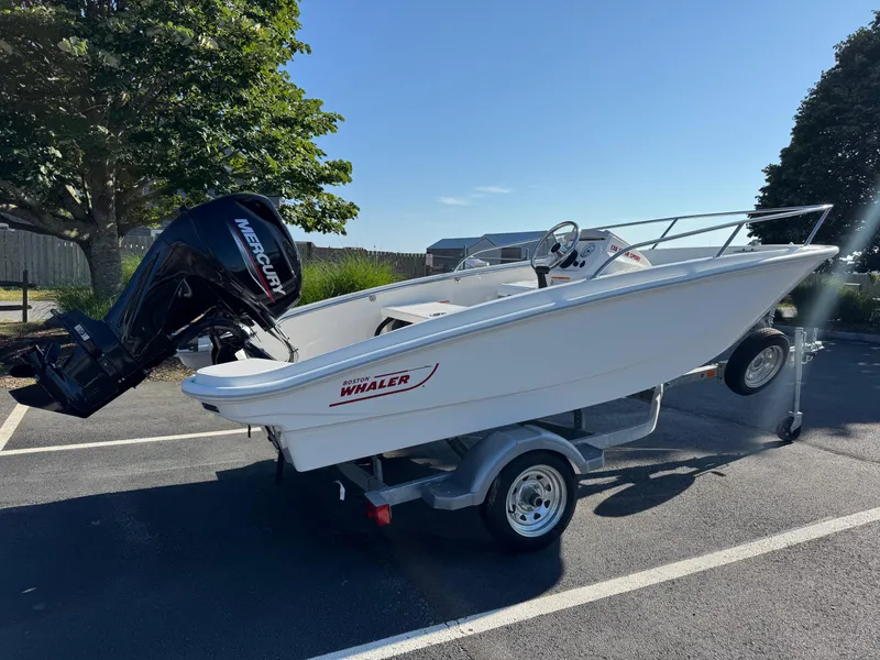 Slide: The Image of 2025 Boston Whaler 130 Super Sport boat on trailer, parked outdoors. - 4